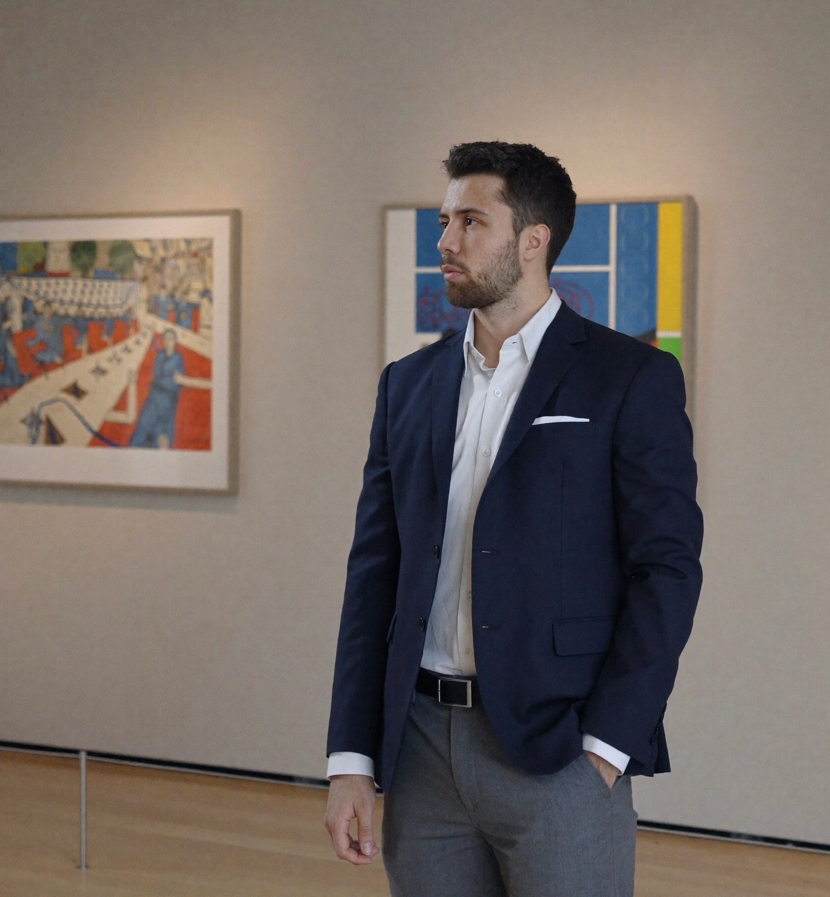 Julius standing in a gallery between two paintings, looking aside.