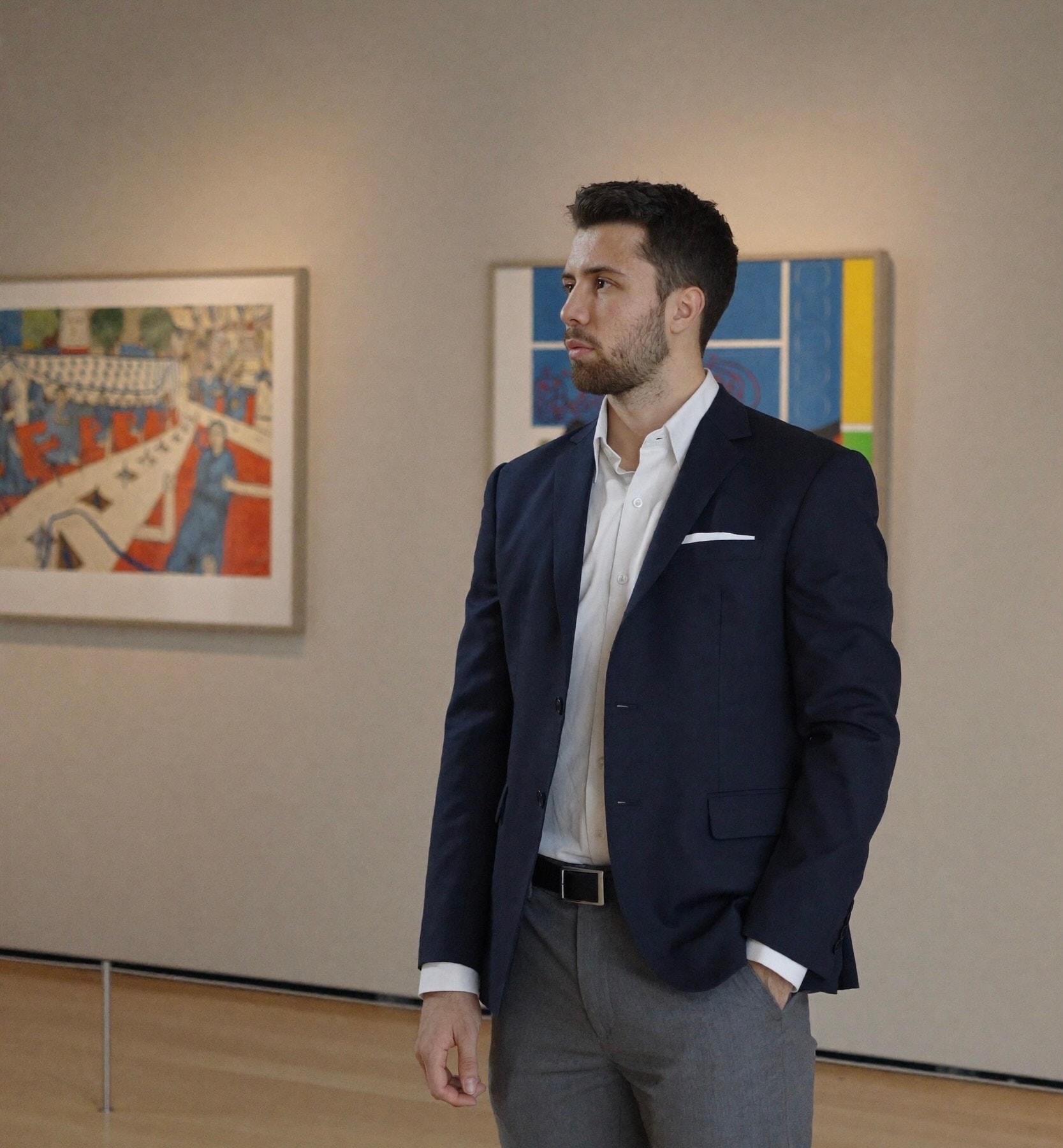 Julius standing in a gallery between two paintings, looking aside.